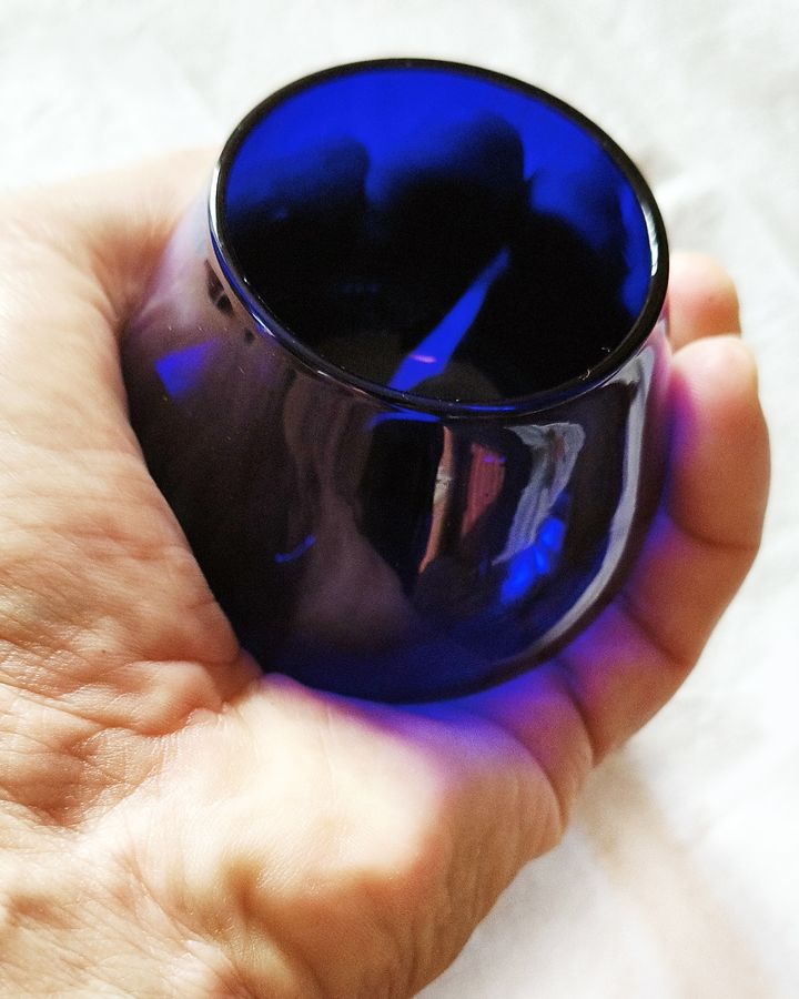 Una mano che regge un calice blu da assaggio